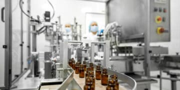 A line of bottles on a conveyor belt in a factory, addressing drug shortages and aiding domestic production regulated by the U.S. government.