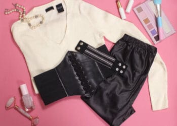 Reduction on black corset, black pants, and jewelry on a pink background.