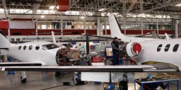 Two men working on a small airplane in a hangar while ensuring increased oversight by the FAA as per Boeing guidelines.