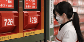 A Japanese woman wearing a face mask looking at a price tag affected by inflation.