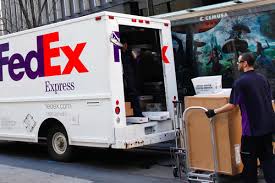 FedEx driver loading packages onto a delivery truck. 2024 shipping discounts. - Supply Chain News