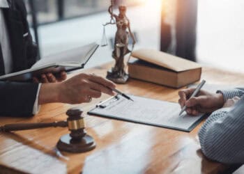 A lawyer from Omaha Industries signing a document as part of a lawsuit involving United Natural Foods Inc., with a gavel.