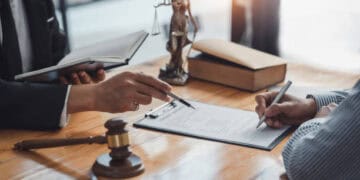 A lawyer from Omaha Industries signing a document as part of a lawsuit involving United Natural Foods Inc., with a gavel.