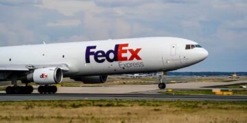 A FedEx plane reconfigures on the runway at an airport.