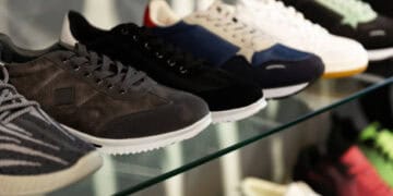 A row of Nike sneakers on a glass shelf, showcasing the company's inventory strategy to meet consumer demand.