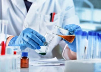 A scientist from China is working in a laboratory with a test tube, studying the impact of Taiwanese chemical imports and tariff concessions.