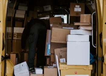 A man performing sorting operations by loading boxes into a UPS van.