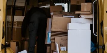 A man performing sorting operations by loading boxes into a UPS van.