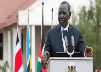Kenyan President, Mwai Kibaki, speaks at a podium in front of flags.