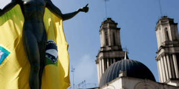 A controversial statue of a woman holding a Brazilian flag in front of a building.
