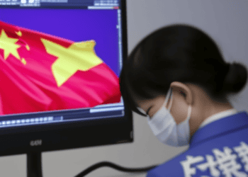 A woman wearing a face mask is looking at a computer screen with a Chinese flag while conducting an investigation for Capvision China.
