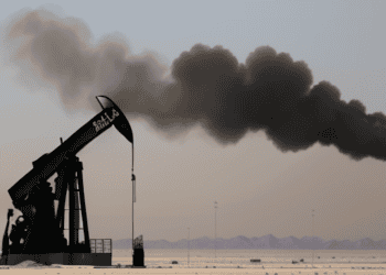 A black smoke billows from an oil pump in the desert, highlighting the potential escalation in Middle East tensions and its impact on oil prices.