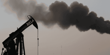 A black smoke billows from an oil pump in the desert, highlighting the potential escalation in Middle East tensions and its impact on oil prices.