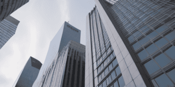 Skyscrapers rise towards a bright sky, illustrating potential economic challenges. - Supply Chain News