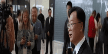 The new US Ambassador to China in a suit speaks to reporters at an airport.