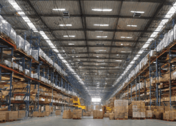 Vast warehouse interior with high shelving units stocked with boxes. Victory Group's strategic expansion. - Supply Chain News