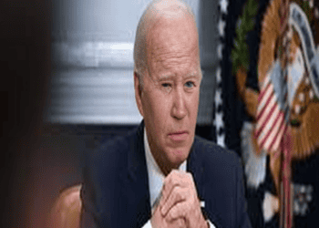 Biden sits at a desk in front of an American flag.
