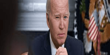 Biden sits at a desk in front of an American flag.