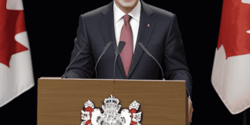 The Canadian Prime Minister, standing at a podium adorned with Canadian flags, addresses the audience on global challenges and foreign policy.