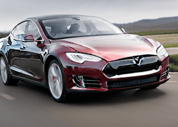 The Tesla Model S, developed by Elon Musk, is driving down the road.
