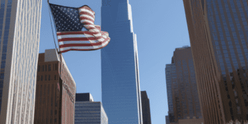 American flag waving against backdrop of skyscrapers, symbolizing strong US economy. - Supply Chain News