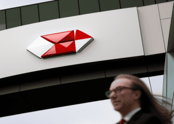 A woman walks past the HSBC building with a red and white logo.