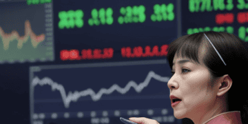 A woman holding a pen and a tablet reflects on Asia Stocks.