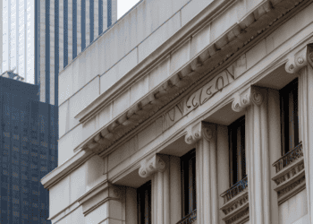 A building with columns and a skyscraper in the background, representing stability in the banking system.