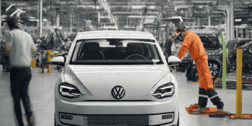 Volkswagen Golf production line worker inspecting a new white Golf. 2023 sales surge. - Supply Chain News
