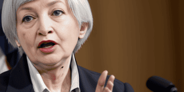 Treasury Secretary Yellen is speaking into a microphone, discussing the economic consequences.