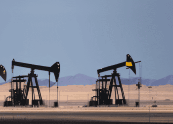 Oil pumps in the desert with mountains in the background, highlighting U.S. Production Disruptions.
