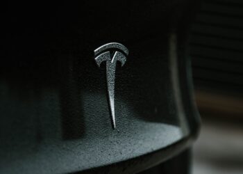 A close up of a Tesla logo on a black car, showcasing Elon Musk's AI leadership.