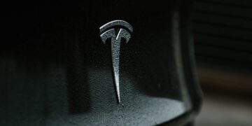 A close up of a Tesla logo on a black car, showcasing Elon Musk's AI leadership.