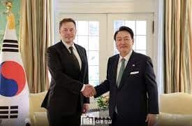 Two men shaking hands in front of South Korean flags.