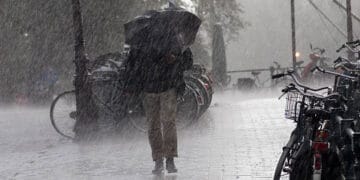 A man adapts to the extreme weather, walking through the rain with an umbrella.