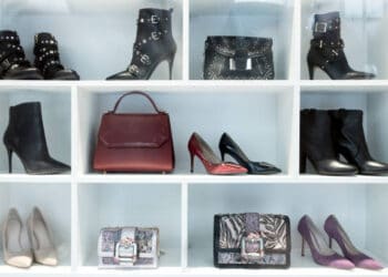 A display of women's shoes and handbags on a white shelf in a luxury retail store.