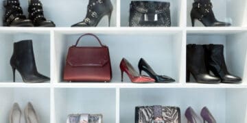 A display of women's shoes and handbags on a white shelf in a luxury retail store.