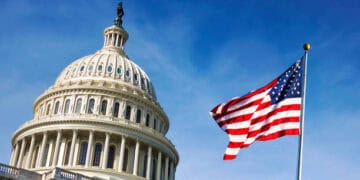 An American flag proudly flies in front of the Capitol building, unaffected by the recent China tariffs or Yellen's statements, standing as a symbol of patriotism amidst Trump's tariff proposal.