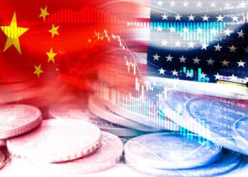 A stack of coins with the US and Chinese flags in the background representing the economic ties and trade relations between the two countries under the Biden Administration and their 2023 Trade Agenda.