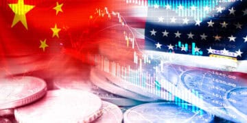 A stack of coins with the US and Chinese flags in the background representing the economic ties and trade relations between the two countries under the Biden Administration and their 2023 Trade Agenda.