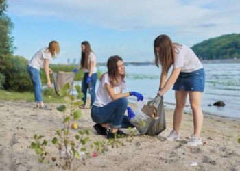 A group of youth-centric girls are picking up trash on the beach as part of a sustainability summit organized by the Bajaj Foundation.