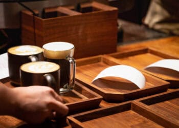 A person is pouring coffee into a wooden tray at Starbucks, amidst a lawsuit filed by the National Consumers League.