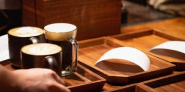 A person is pouring coffee into a wooden tray at Starbucks, amidst a lawsuit filed by the National Consumers League.