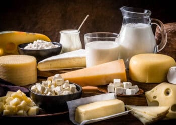 Various types of cheese from US and Canada's dairy market on a wooden table, highlighting the ongoing trade dispute.