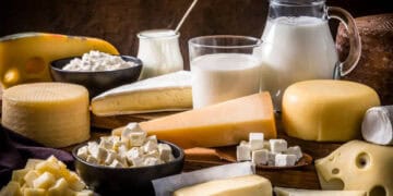 Various types of cheese from US and Canada's dairy market on a wooden table, highlighting the ongoing trade dispute.