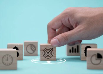 A hand is preparing wooden blocks with business icons for future challenges.