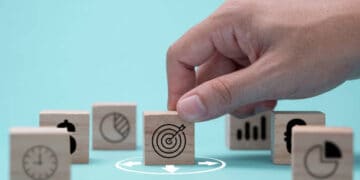 A hand is preparing wooden blocks with business icons for future challenges.