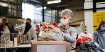 A woman, possibly a UN official, is putting clothes into a box.