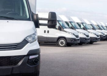A row of white vans parked in a parking lot, showcasing the advantages of local sourcing.