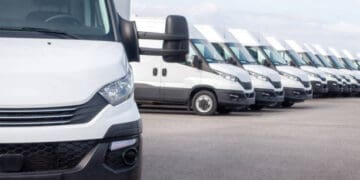 A row of white vans parked in a parking lot, showcasing the advantages of local sourcing.